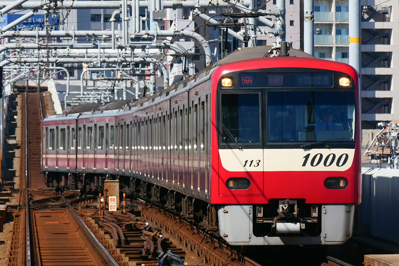 An Airport Express bound for Haneda Airport, formed of Keikyu 1000 type set 1113, enters Kojiya Station on the Keikyu Airport Line.